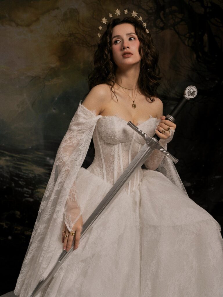 A woman in a white lace gown holding a silver sword against a dark background.